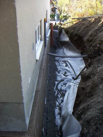 Dräneringsgrav längs en husgrund med dräneringsrör och fiberduk